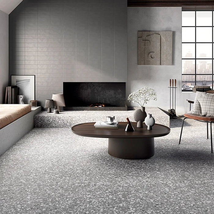 Salotto con pavimento in gres porcellanato effetto graniglia e marmetta. Collezione Venexia di Alfalux, formato 120x120 cm, colore Murano Grigio con marmette bianche, avorio e grigie scuro