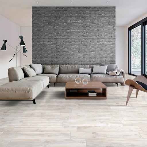Salotto con divano tortora e pavimento in gres porcellanato effetto legno rustico della collezione Living di Ceramica Rondine, formato 15x100 cm, colore Avorio