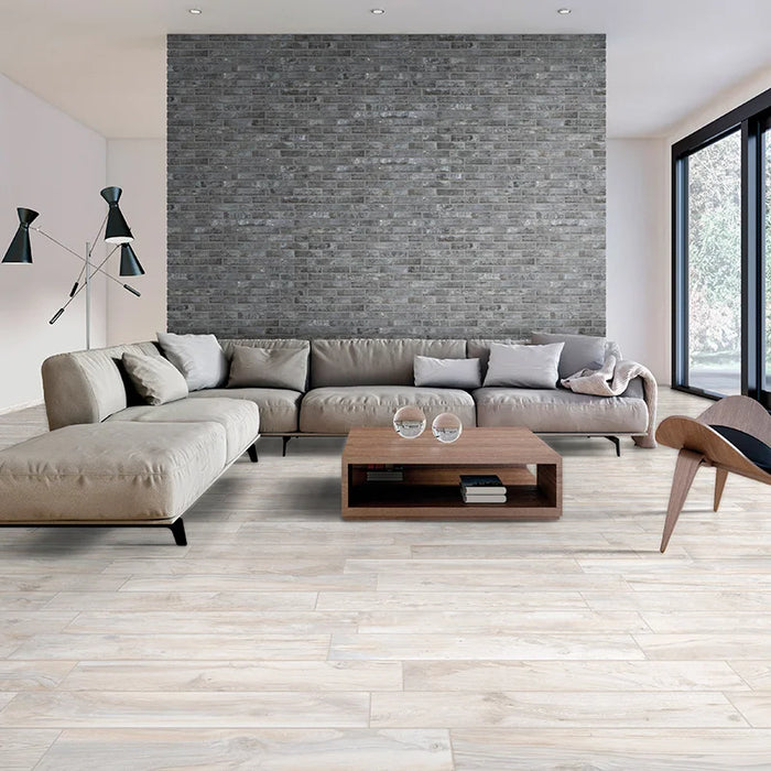 Salotto con divano tortora e pavimento in gres porcellanato effetto legno rustico della collezione Living di Ceramica Rondine, formato 15x100 cm, colore Avorio