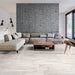 Salotto con divano tortora e pavimento in gres porcellanato effetto legno rustico della collezione Living di Ceramica Rondine, formato 15x100 cm, colore Avorio
