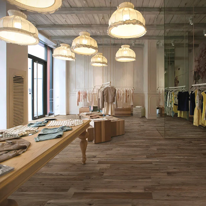 Negozio di vestiti con pavimento in gres porcellanato effetto legno rustico della collezione Living di Ceramica Rondine, formato 15x100 cm, colore Noce