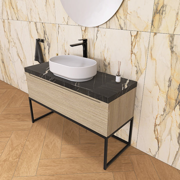 Un moderno mobile da bagno a terra, solido e di grande impatto visivo, grazie alla particolare cornice in metallo nero opaco, che crea un gioco di colore con la base cannettata orizzontale che contraddistingue la serie Penelope.
Altro filo conduttore della serie è il top scatolare nella particolare finitura marmo Nero marquinia.
Penelope 06 è un mobile audace e duraturo, che gioca con colori e materiali, al contempo elegante ed estremamente moderno.
Disponibile nelle finiture: Tortora Opaco, Bianco 