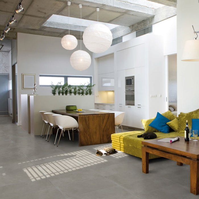 Casa moderna con cucina bianca e tavolo in legno, divano in tessuto verde/giallo e pavimento in gres porcellanato smaltato opaco effetto cemento nuvolato dai toni caldi della collezione Baya di Paul & Co Ceramiche, formato 30x60, colore Grey