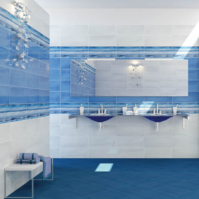 Bagno bianco e blu con doppio lavandino sospeso blu e muro con rivestimento con design astratto ispirato al mare, piastrella lucida dai colori vivaci della collezione Caribe di Paul & Co Ceramiche, formato 20x50, colore Paraiso Blue