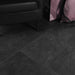 dettaglio con poltrona nera in pelle, borse rosa perla e pavimento in gres porcellanato smaltato opaco effetto pietra naturale ardesia della collezione Ecoslate di Paul & Co Ceramiche, formato 90x90, colore Black
