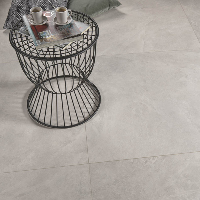 dettaglio salotto con tavolino moderno e cuscini appoggiati su pavimento in gres porcellanato smaltato opaco effetto pietra naturale ardesia della collezione Ecoslate di Paul & Co Ceramiche, formato 90x90, colore White