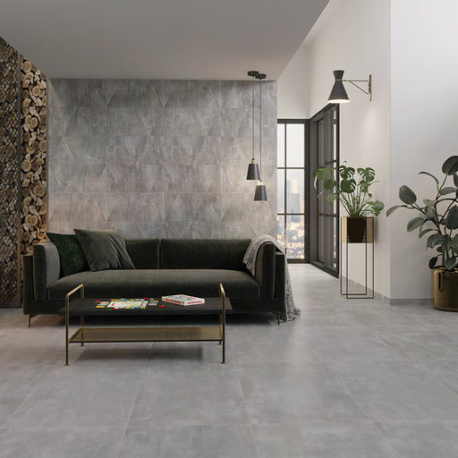 Salotto moderno con divano in tessuto e pavimento in gres porcellanato smaltato effetto cemento della collezione More! di Paul & Co Ceramiche, formato 60x120, colore Grey