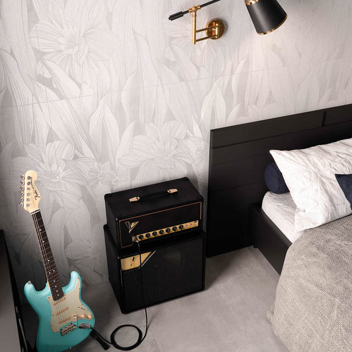 dettaglio camera da letto moderna con letto nero e chitarra elettrica azzurra, muro con rivestimento in gres porcellanato smaltato opaco effetto cemento DECORATO FLOREALE con dettagli tono su tono della collezione More! di Paul & Co Ceramiche, formato 60x120, colore Precious Ice