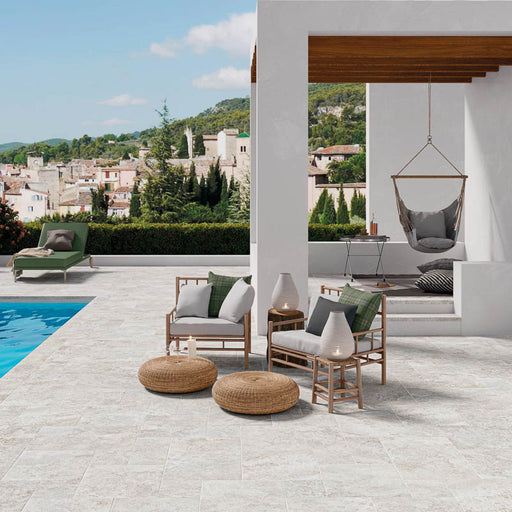 Spazio esterno con sedie in tessuto grigio chiaro a bordo piscina, pavimento per esterni in gres porcellanato smaltato opaco effetto pietra naturale francese della collezione Occitanie di Paul & Co Ceramiche, formato modulare multiformato antiscivolo R11, colore Grey