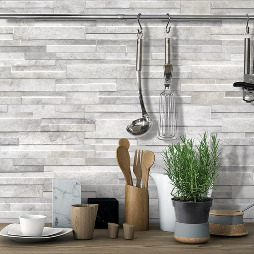 Dettaglio cucina con utensili in legno e pianta di rosmarino, muro rivestito in gres porcellanato effetto muretto a incastro della collezione quarzo nella colorazione Grey di Keradom