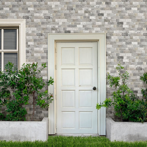 Facciata casa con piante e porta bianca, rivestimento muro in gres porcellanato decorato della collezione Roma di Keradom nella colorazione Grey