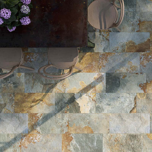 Spazio esterno con tavolo e sedie in legno, fiori viola e pavimento in gres porcellanato smaltato effetto pietra naturale di Bali della collezione Thai di Paul & Co Ceramiche, formato 30x60 grip antiscivolo R11 per esterni, colore Tegalan Vert