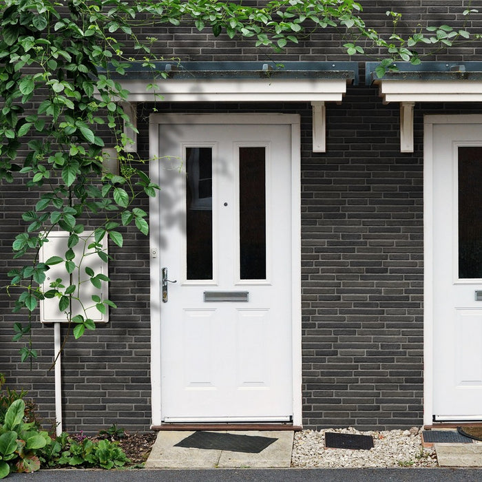 Facciata casa con doppi entrata, porte in legno bianche e piante, facciata rivestita con gres porcellanato effetto mattone in rilievo della collezione Urban di Keradom nella colorazione Chicago