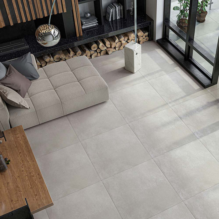 Salotto con divano in tessuto grigio. pavimento in gres porcellanato effetto pietra e cemento di Idea Ceramica. Serie Urban Stone colore Greyge