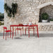 Giardino con tavolo rosso e pavimento Colosseum Ivory di Idea Ceramica in gres porcellanato effetto pietra 60x60 cm con bordo irregolare anticato per esterni rustici