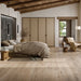 Camera da letto moderna rustica con travi in legno e pavimento in gres porcellanato effetto legno rustico della collezione Cortina di Ceramica Rondine, formato 24x150 cm, colore Beige