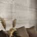 Dettaglio salotto con cuscini marroni e rivestimento in gres porcellanato effetto cemento industriale della collezione Docks di Ceramica Rondine, formato 60x120 cm, colore Taupe