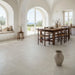 Casa moderna con tavolo rustico e pavimento Elea Ivory di Idea Ceramica in gres porcellanato effetto pietra e cemento 90x90 cm