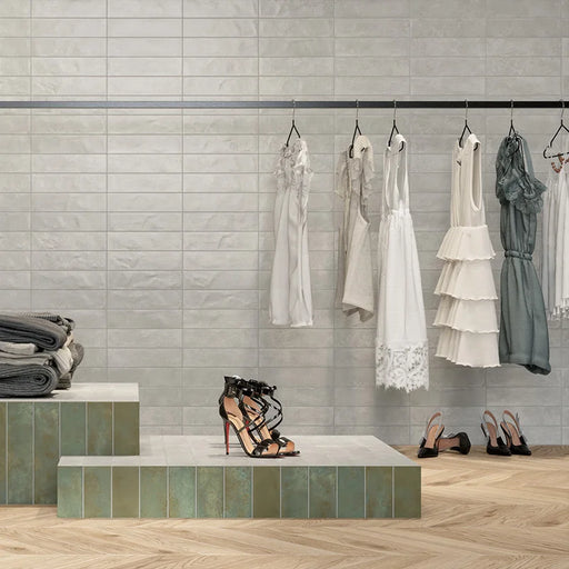 Negozio d'abbigliamento con rivestimento in gres porcellanato serie Miniature Fuoco di Marca Corona, effetto mattoncino e metallo ossidato, formato 6x24 cm, Colore Bianco Argeteo