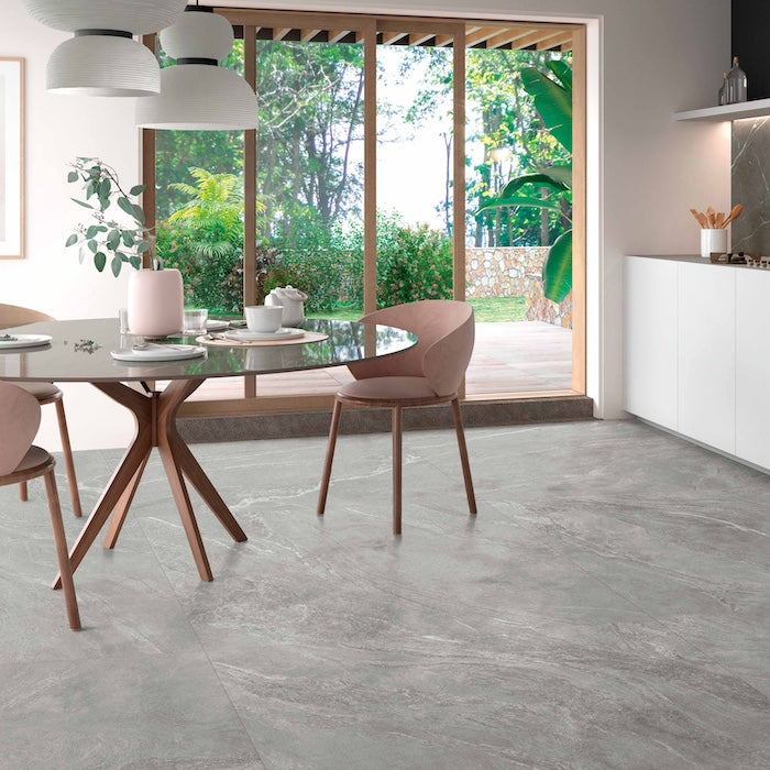 cucina moderna bianca con tavolo in vetro, porta vetro scorrevole sul giardino e pavimento interno in gres porcellanato effett pietre naturali della collezione La geoteca di Gardenia Orchidea nella colorazione Brennero formato 120x120