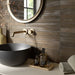 Dettaglio bagno con lavabo nero, rubinetteria oro e rivestimento in gres porcellanato effetto mattoncino della collezione Iridescent di Ceramica Rondine, formato 4.8x45 cm, colore Moka