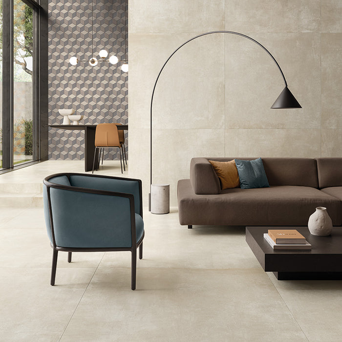 salotto con poltrona in tessuto blu, dovano marrone e lampada moderna, pavimento e rivestimento in gres porcellanato effetto cemento industriale. Noord di ceramiche keope 80x80 colore Ivory 