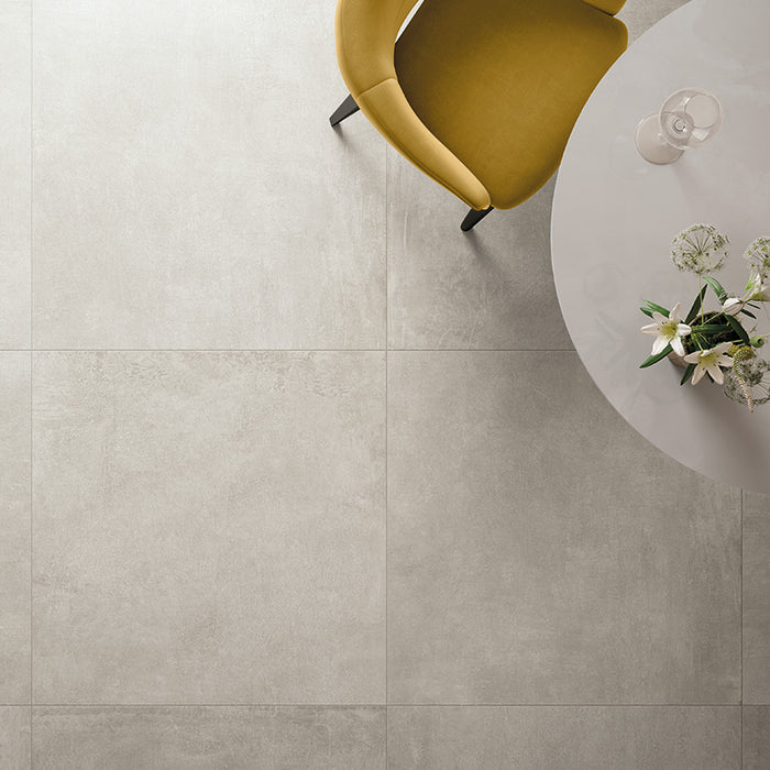 Dettaglio tavolo ristorante con sedia gialla su pavimento in gres porcellanato effetto cemento industriale. Noord di ceramiche keope 60x60 colore Silver 