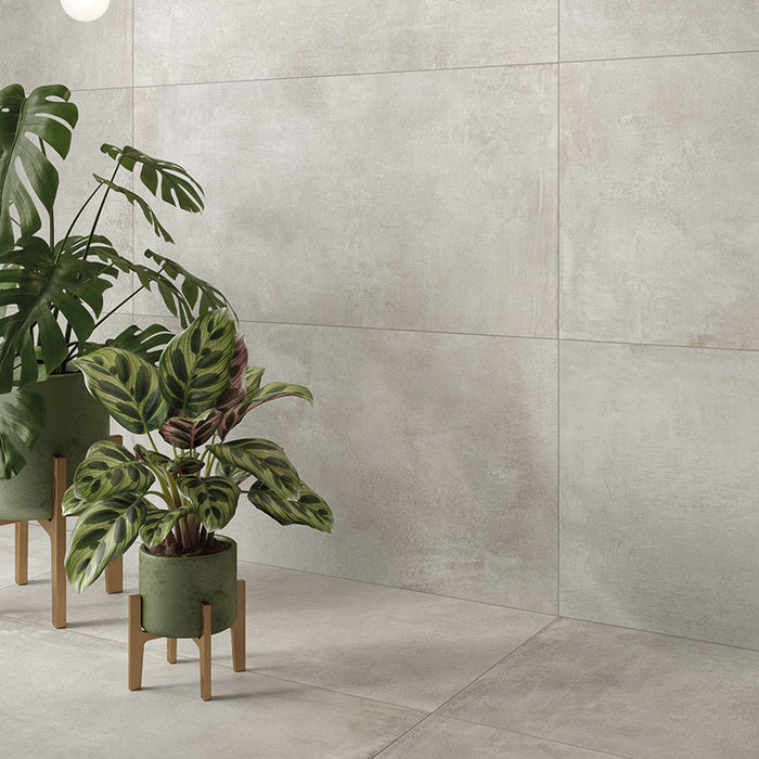 Dettaglio angolo salotto con piante, pavimento e rivestimento in gres porcellanato effetto cemento industriale. Noord di ceramiche keope 60x120 colore Silver 