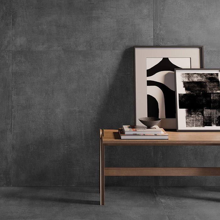 dettaglio tavolino con quadri e libri, pavimento e rivestimento in gres porcellanato effetto cemento industriale. Noord di ceramiche keope 120x120 colore Anthracite