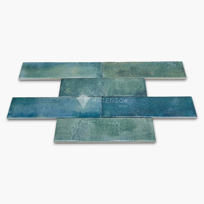 Rivestimento in gres porcellanato effetto mattoncino lucido 6x25 cm, collezione Mojave Sea Water di Ceramica Rondine. Piastrelle blu e verdi con posa a correre sfalsata per pareti di bagno e cucina.