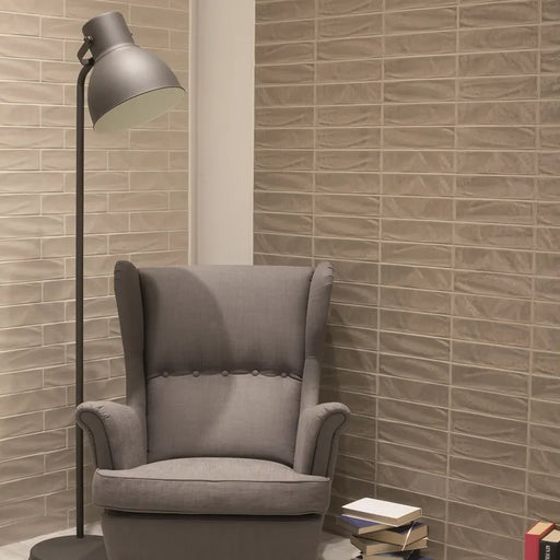 Ambientazione di un salotto con una poltrona rivestito con Decoro a Mattoncino collezione New Yorker di Settecento Ceramica, Caramel 7,5x30