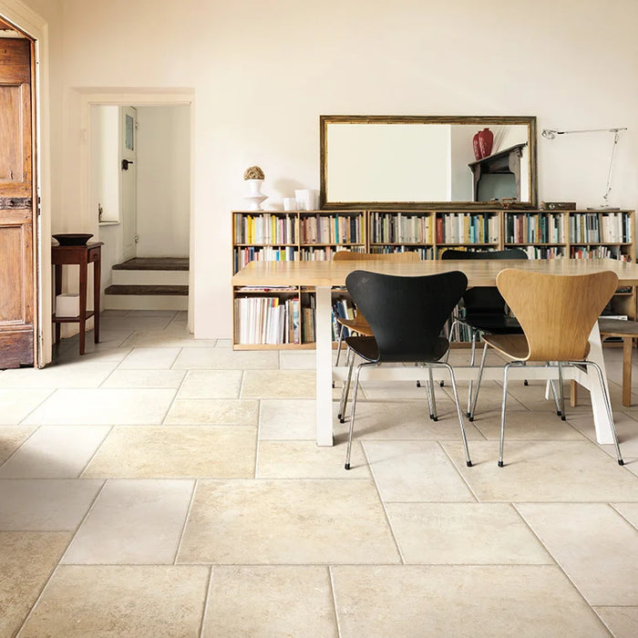 Soggiorno con libreria e pavimento in gres porcellanato effetto pietra leccese della collezione Terre d'Otranto di Ceramica Rondine, formato 60x60 cm con bordo naturale, colore Blend