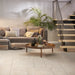 Salotto con divano grigio e scala n legno, pavimento in gres porcellanato effetto pietra leccese della collezione Terre d'Otranto di Ceramica Rondine, formato 60x60 cm con bordo naturale, colore Ivory