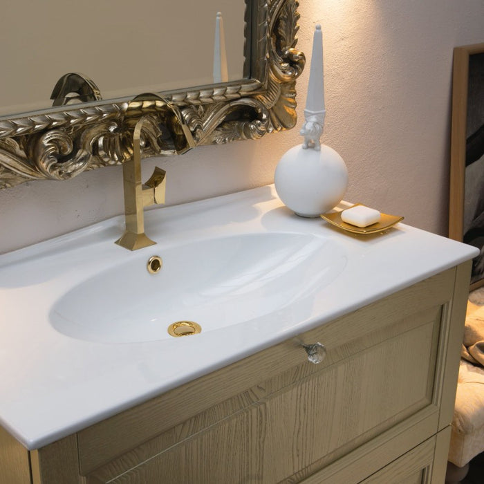 dettaglio del mobile da bagno classico Dorian con lavabo in ceramica bianca, legno massello in finitura dorata champagne e pomelli in cristallo