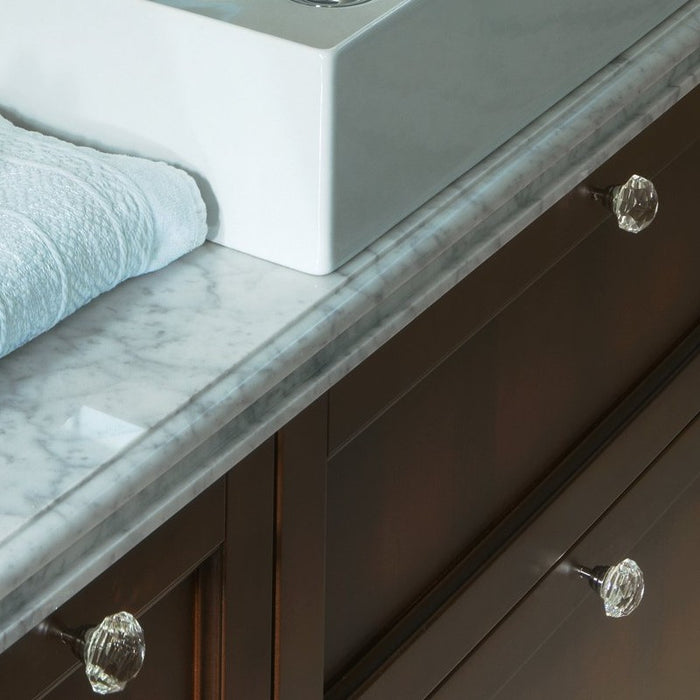 dettaglio del piano in marmo di carrara con bordo lavorato e pomoli con base cromo e cristallo trasparente tipici della composizione mobile da bagno classico dorian. Vista delle ante a telaio in noce antico