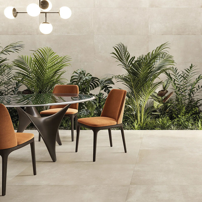 soggiorno con tavolo tondo in vetro, pavimento e rivestimento in gres porcellanato effetto cemento industriale. Noord di ceramiche keope 30x60 colore Ivory 