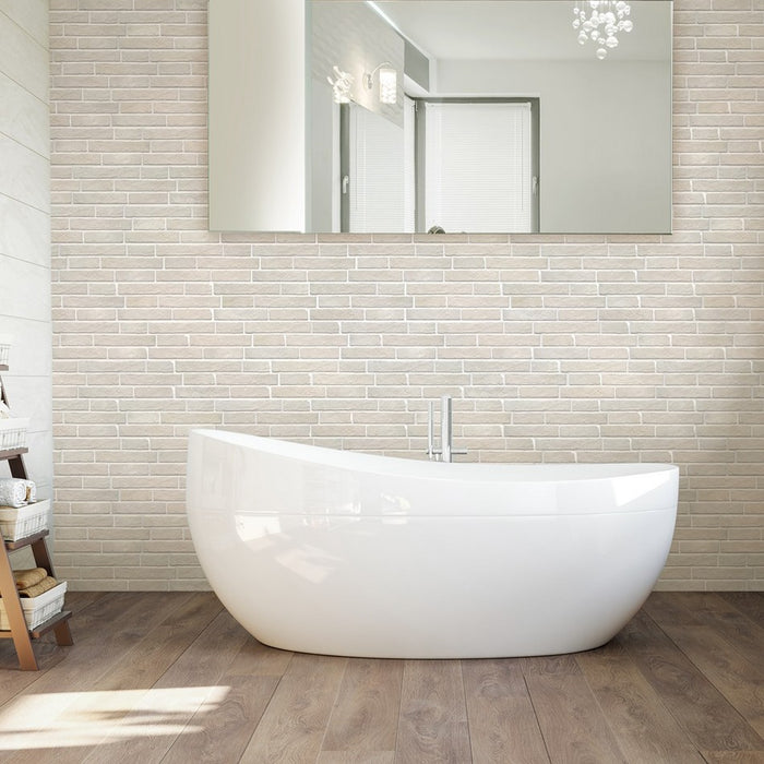 Bagno con vasca freestanding e parete rivestita in gres porcellanato effetto mattone. Collezione Dany di Walls and More by keradom. Colore Vaniglia